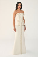 Woman wearing a strapless, buttoned-up dress with a long skirt on a white background