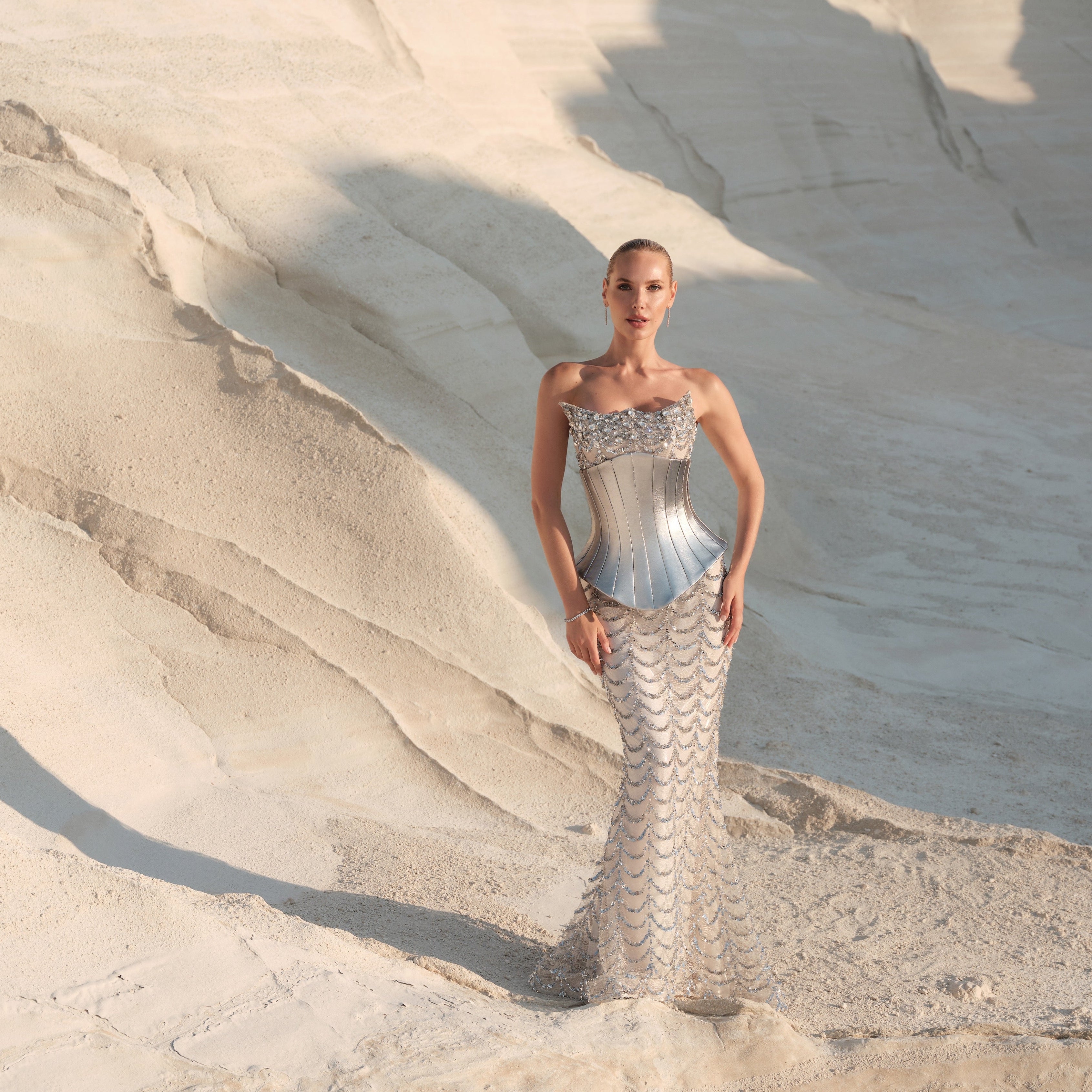 Woman in a silver dress standing on a textured beige surface