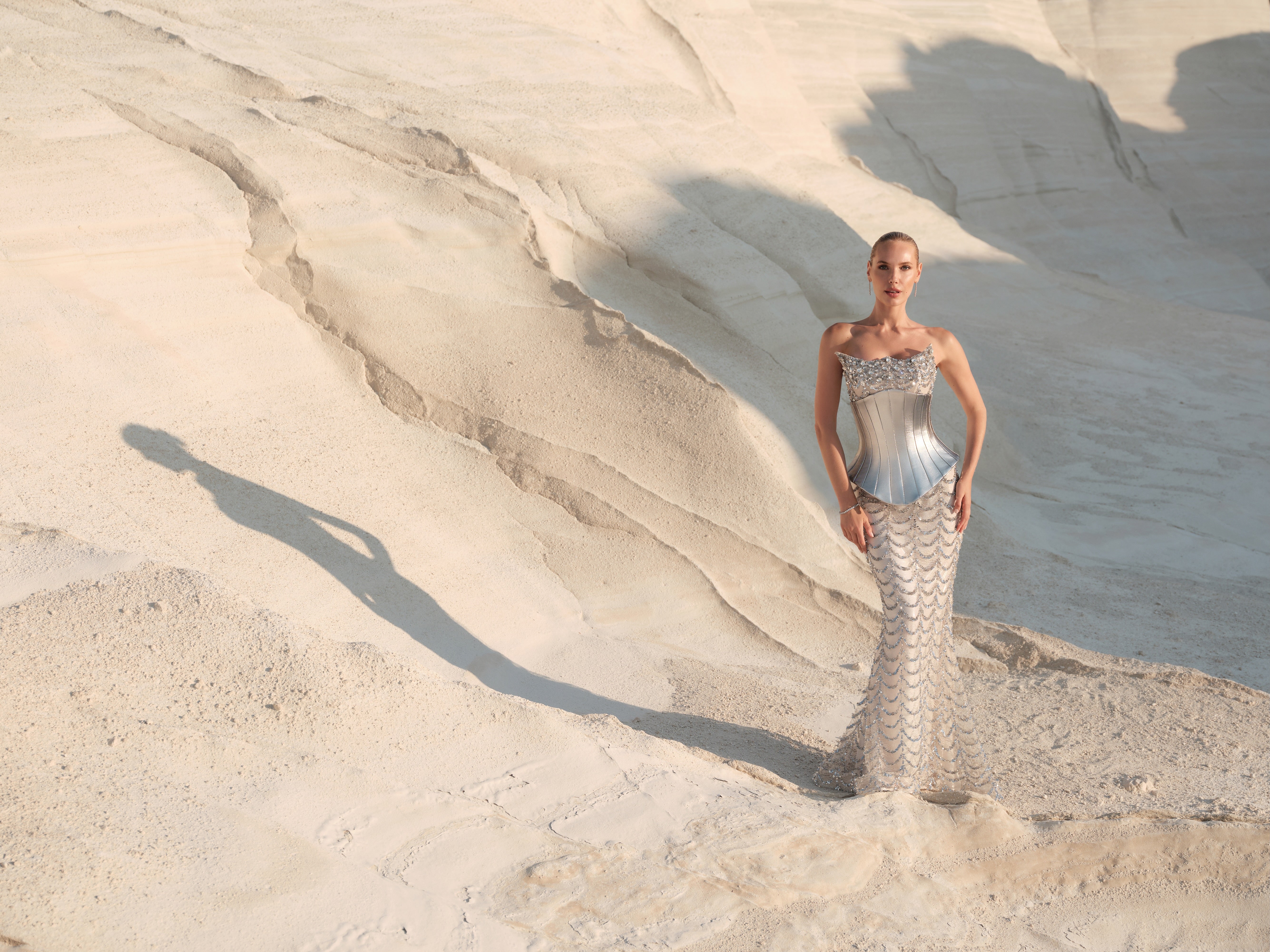 Woman in a silver dress standing on a textured beige surface