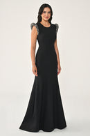 Woman wearing a black evening gown with embellished shoulders on a white background