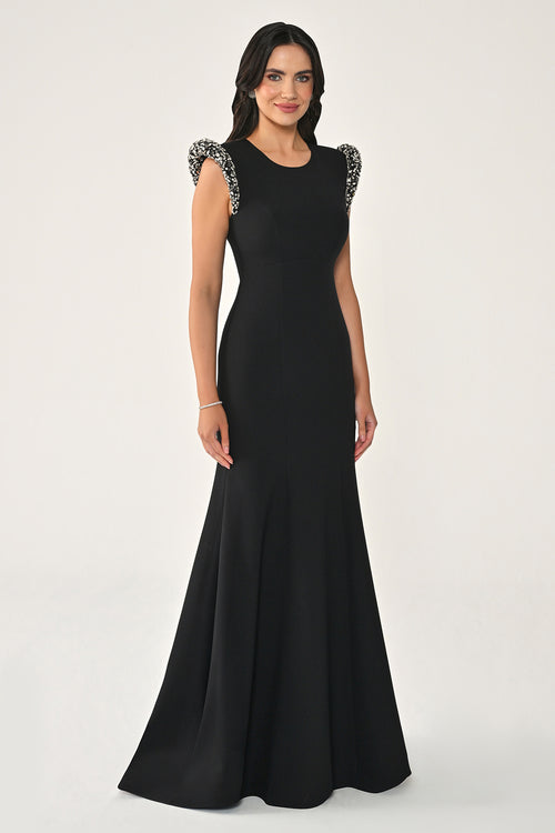 Woman wearing a black evening gown with embellished shoulders on a white background