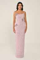 Woman wearing a pink strapless gown with floral embellishments on a beige background