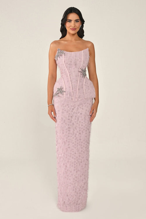 Woman wearing a pink strapless gown with floral embellishments on a beige background
