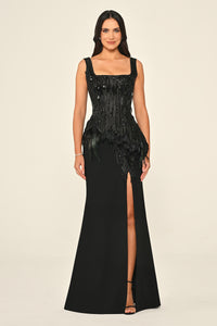 Woman wearing a black evening gown with feather details on a beige background