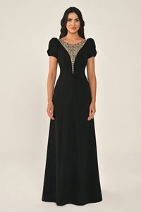 Woman wearing a black evening gown with a beaded neckline on a beige background