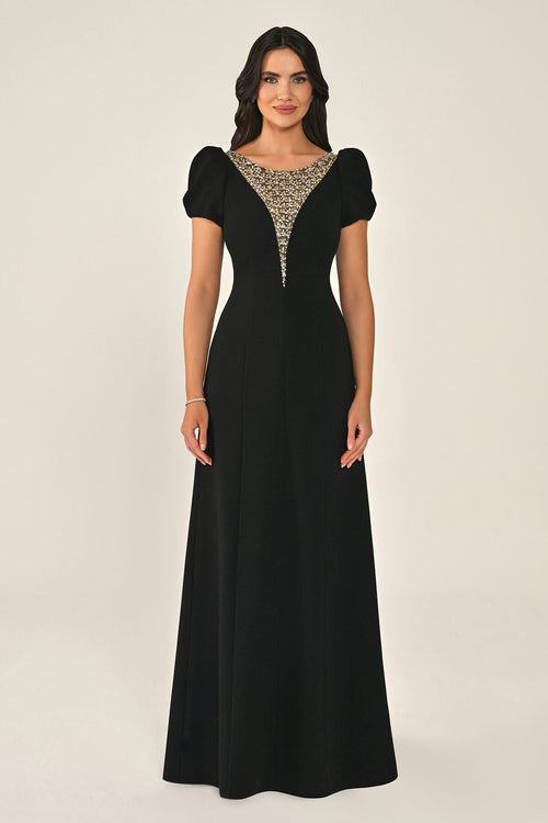 Woman wearing a black evening gown with a beaded neckline on a beige background