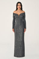 Woman wearing a long, dark gray off-shoulder dress with intricate detailing on a white background