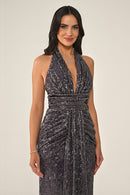 Woman wearing a sparkly black dress against a beige background