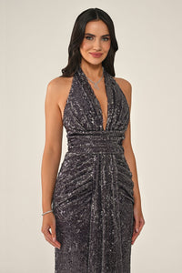 Woman wearing a sparkly black dress against a beige background