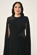 Woman wearing a black dress with embellishments on a white background