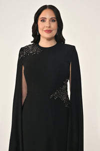 Woman wearing a black dress with embellishments on a white background