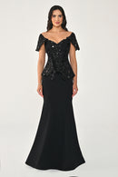 Woman wearing a black evening gown with sequin top on a white background