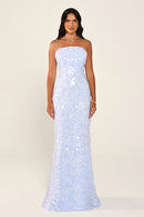 A woman modeling a strapless light blue sequined gown against a plain cream studio background.