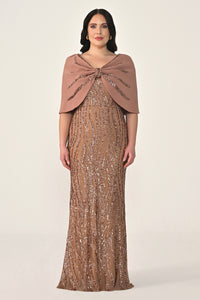 Woman wearing a sparkly brown dress with a matching shawl on a white background