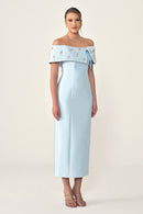 Woman wearing a light blue off-shoulder dress with floral details on a white background