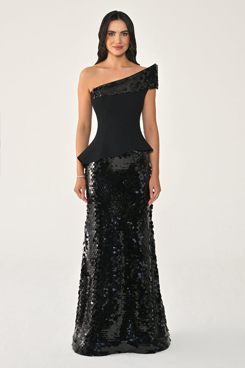 Woman wearing a black one-shoulder dress with sequin skirt on a white background