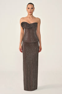 Woman wearing a strapless, sequined evening gown on a white background