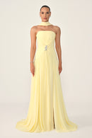Woman wearing a light yellow strapless gown on a plain background