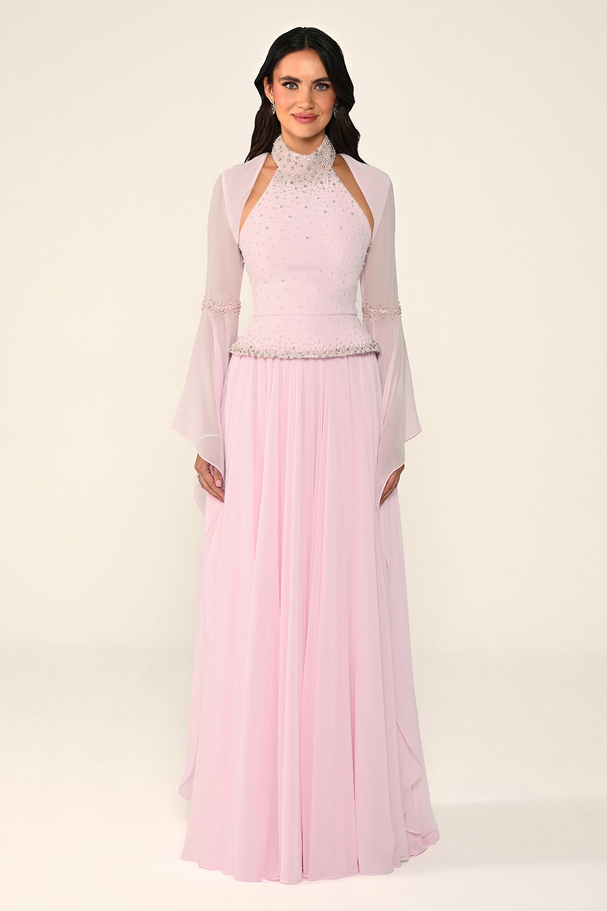 Woman wearing a light pink traditional outfit with a sheer overlay on a white background