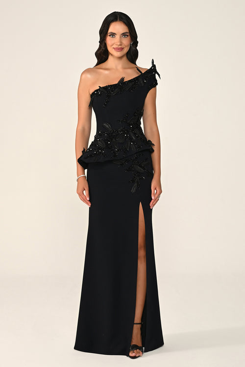 Woman wearing a black one-shoulder evening gown with beading on a beige background