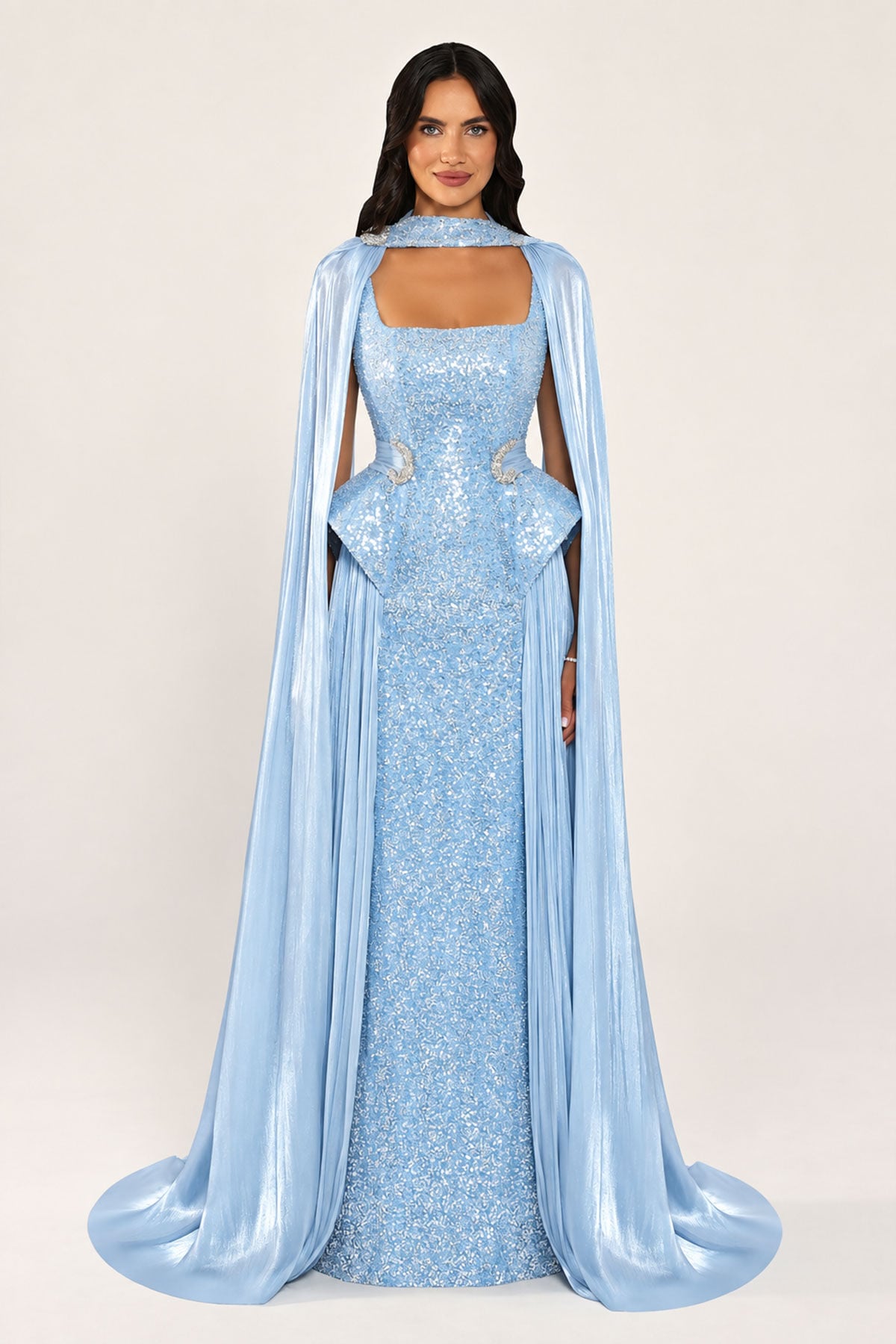 Celestara Dress in Blue: sequin column gown with a square neckline, peplum hip detail, stone-embellished waist and a flowing organza cape