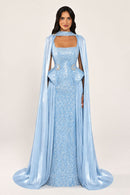 Celestara Dress in Blue: sequin column gown with a square neckline, peplum hip detail, stone-embellished waist and a flowing organza cape