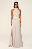 A woman modeling a sleeveless floor-length gown with a high mock neck, a shimmering beaded bodice, and a flowing satin skirt in a light champagne and blush beige tone, set against a plain cream studio background.