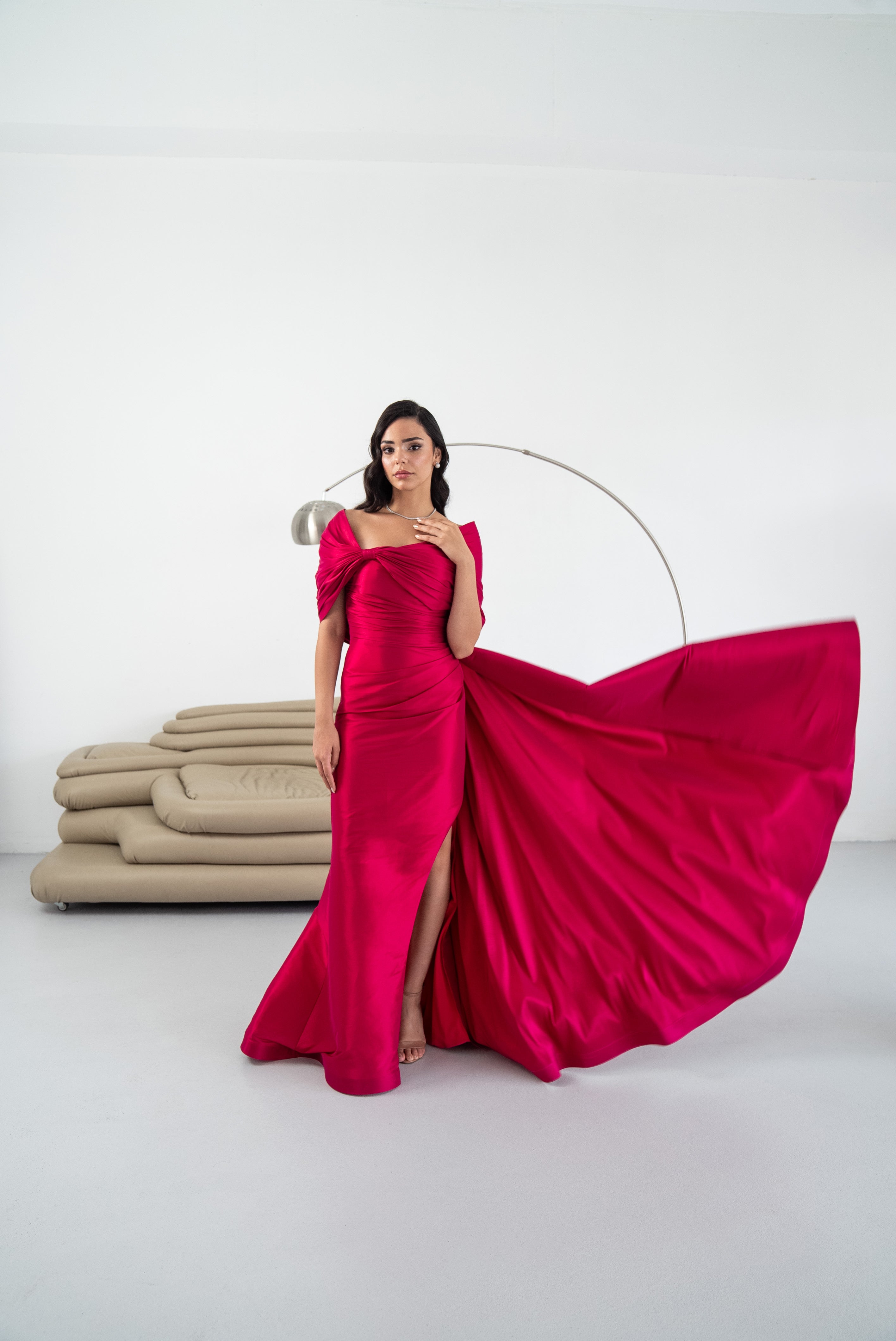 Woman in a vibrant pink gown standing against a white background