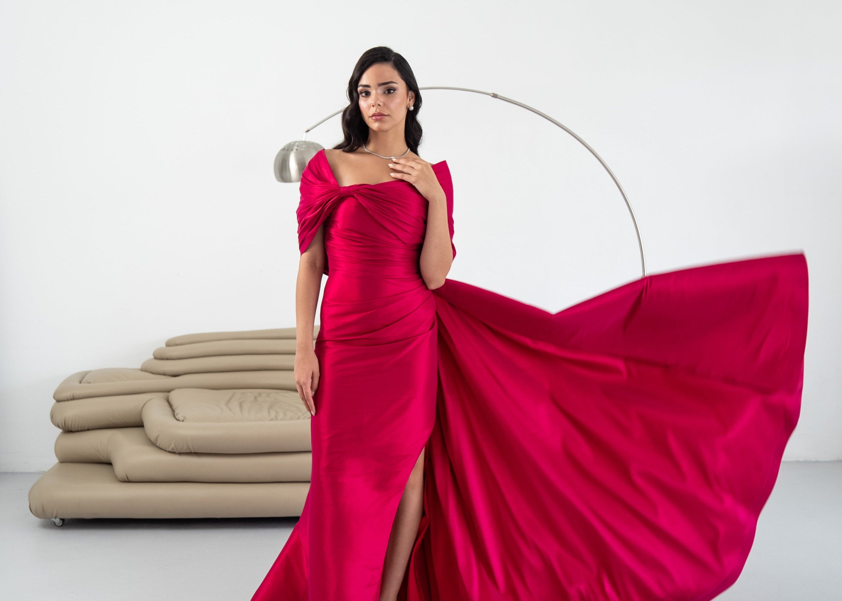 Woman in a vibrant pink gown with a flowing skirt on a white background