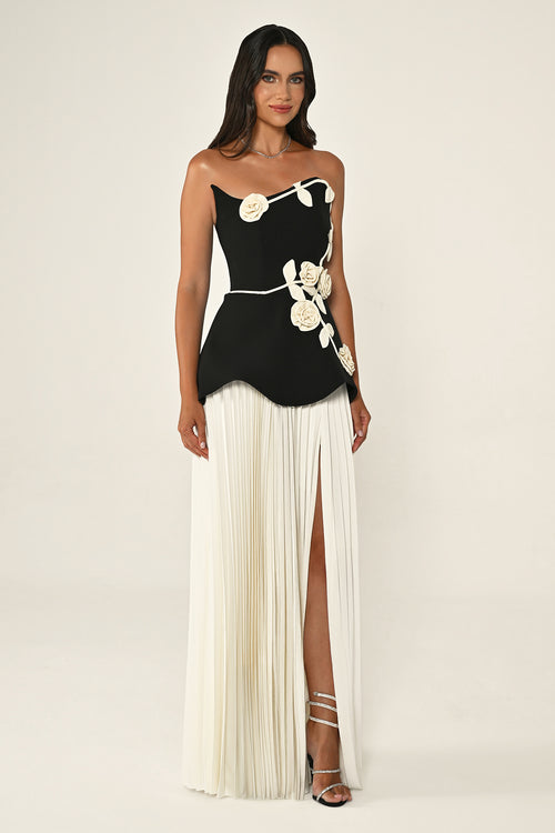 Woman wearing a black and white dress with floral details on a beige background