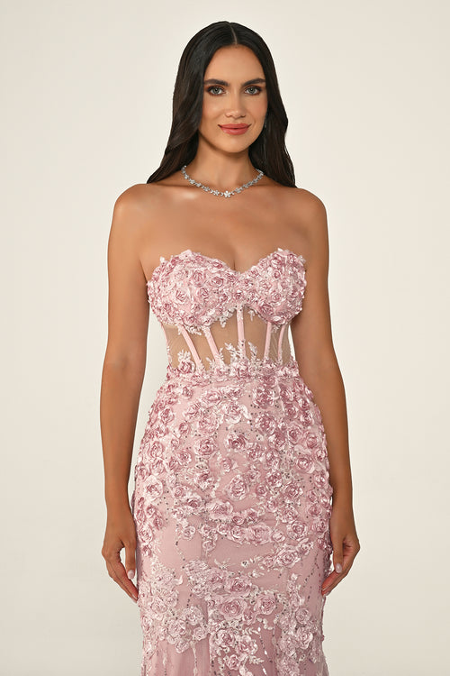Woman wearing a pink strapless gown with floral embroidery on a beige background