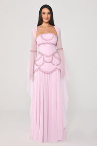 Woman wearing a pink evening gown with sheer sleeves on a white background