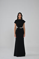 Woman wearing a black dress with a white belt on a gray background