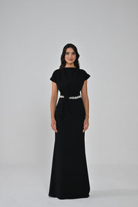 Woman wearing a black dress with a white belt on a gray background