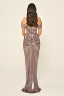 Woman wearing a metallic off-shoulder evening gown on a beige background