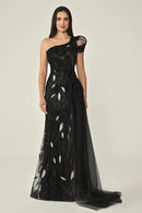 Woman wearing a black one-shoulder evening gown with feather details on a plain background