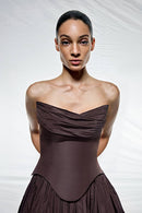 Woman wearing a strapless brown dress against a white background