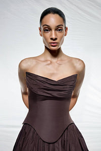 Woman wearing a strapless brown dress against a white background