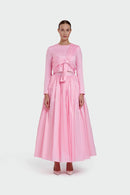 Woman wearing a pink dress with a bow detail on a white background