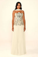 A woman modeling a strapless formal gown with a heavily embellished sequined bodice in black, white, and silver, and a flowing cream tulle skirt, photographed against a plain light background.