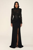 Vespera black maxi evening dress with long sleeves, high neck, sequinned floral lace bodice and tie-waist skirt with leg slit